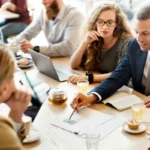 A group of business advisors in a meeting, analyzing a document to plan a client's successful company sale strategy.